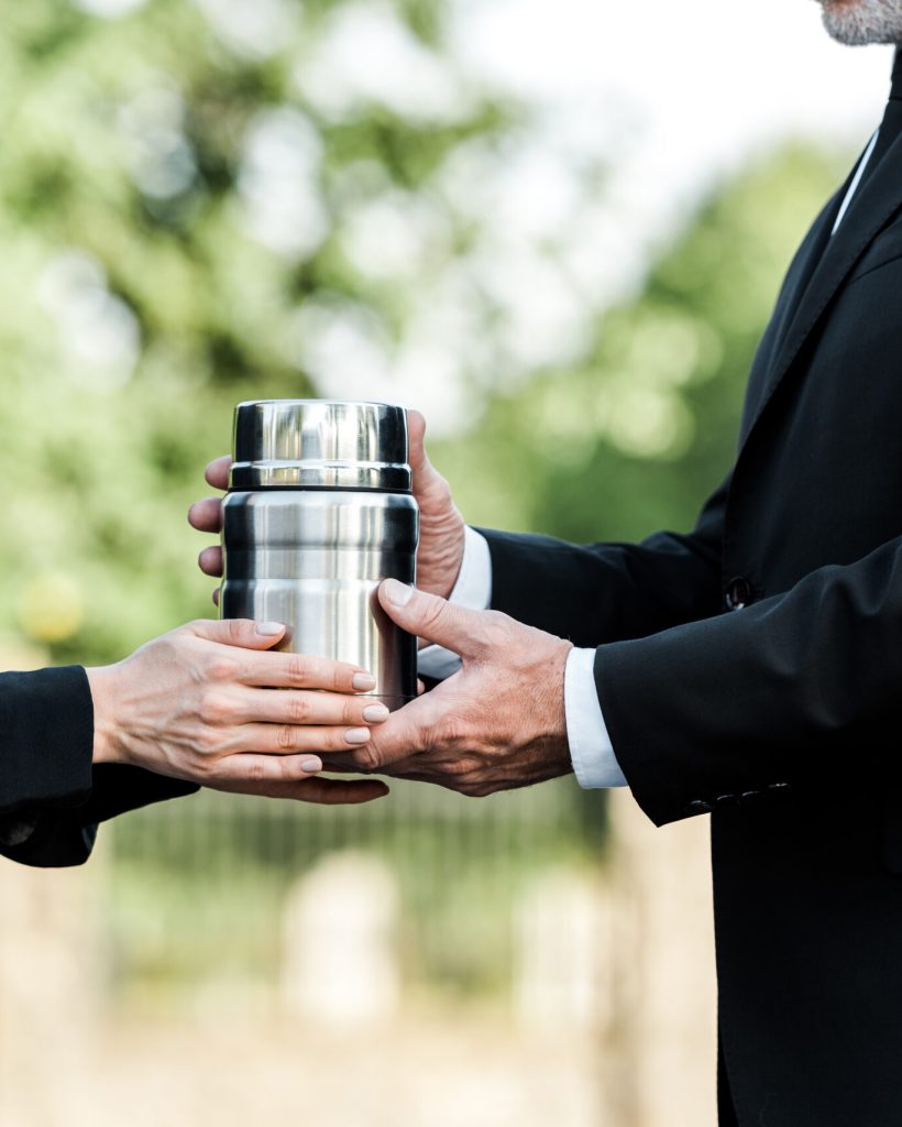 cropped view of senior man and woman holding mortuary urn