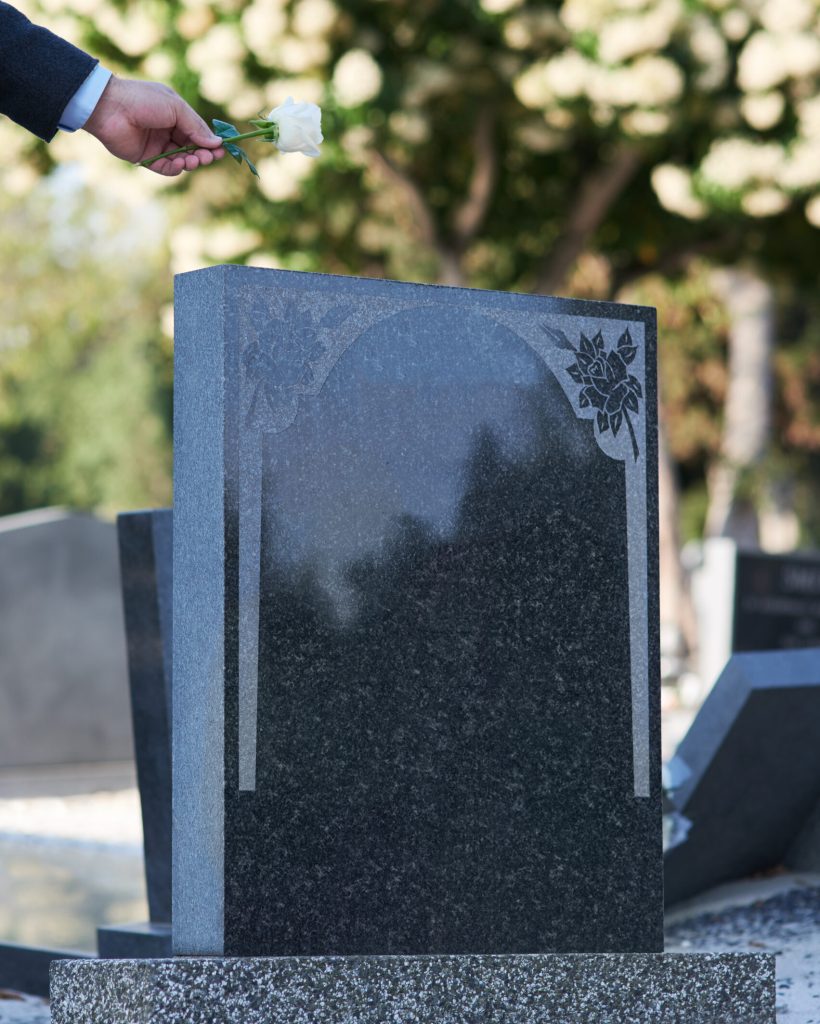 The final goodbye. Cropped shot of a man placing a white rose on a grave