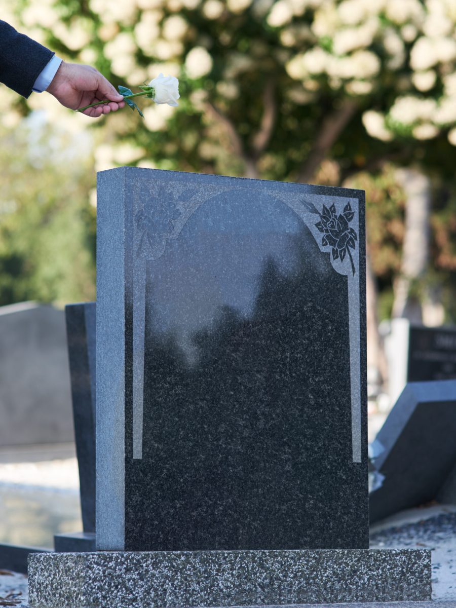 The final goodbye. Cropped shot of a man placing a white rose on a grave